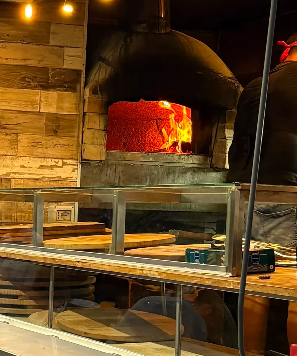 Il forno a legna acceso dentro il camion, con le pale e i taglieri appoggiati al banco
