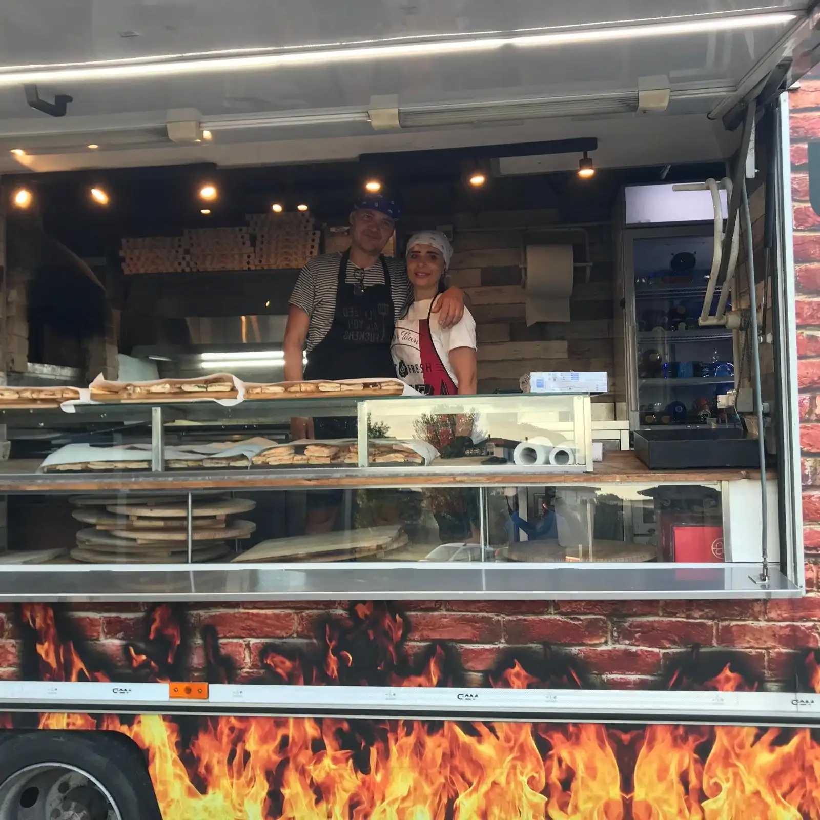 Due pizzaioli al banco del camion, con le schiacciate in mostra