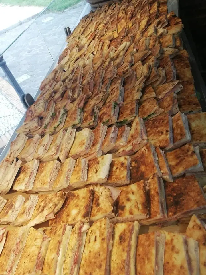Tranci di schiacciata dorata appena usciti dal forno, allineati sul banco