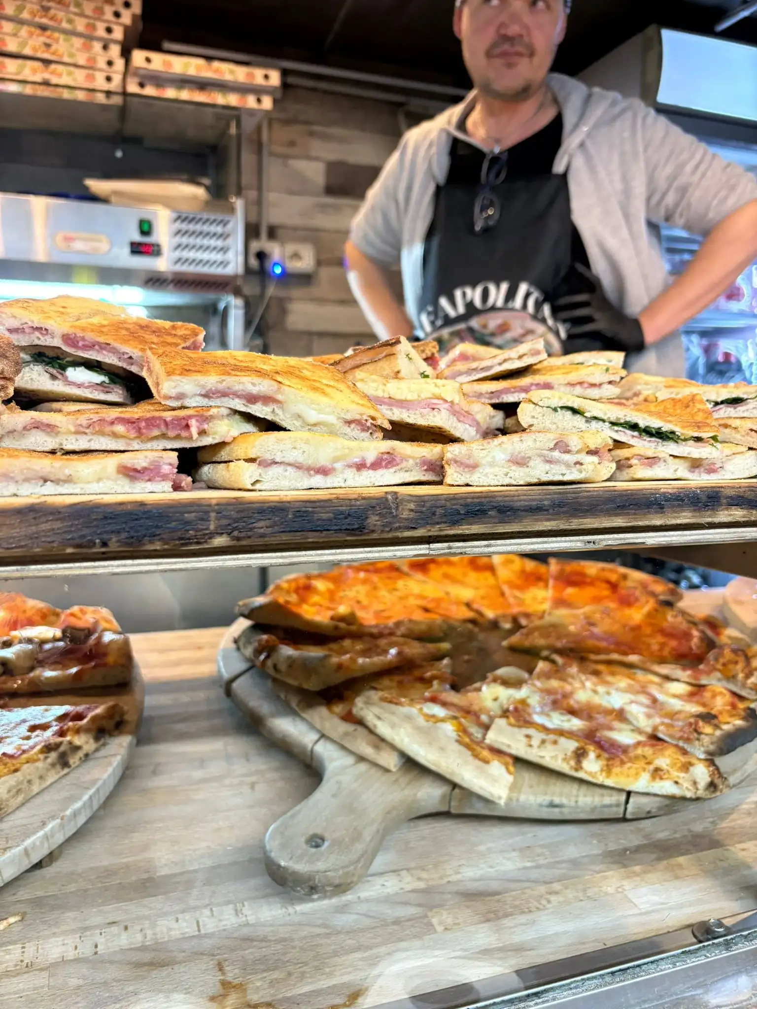 Il pizzaiolo dietro al banco pieno di schiacciate