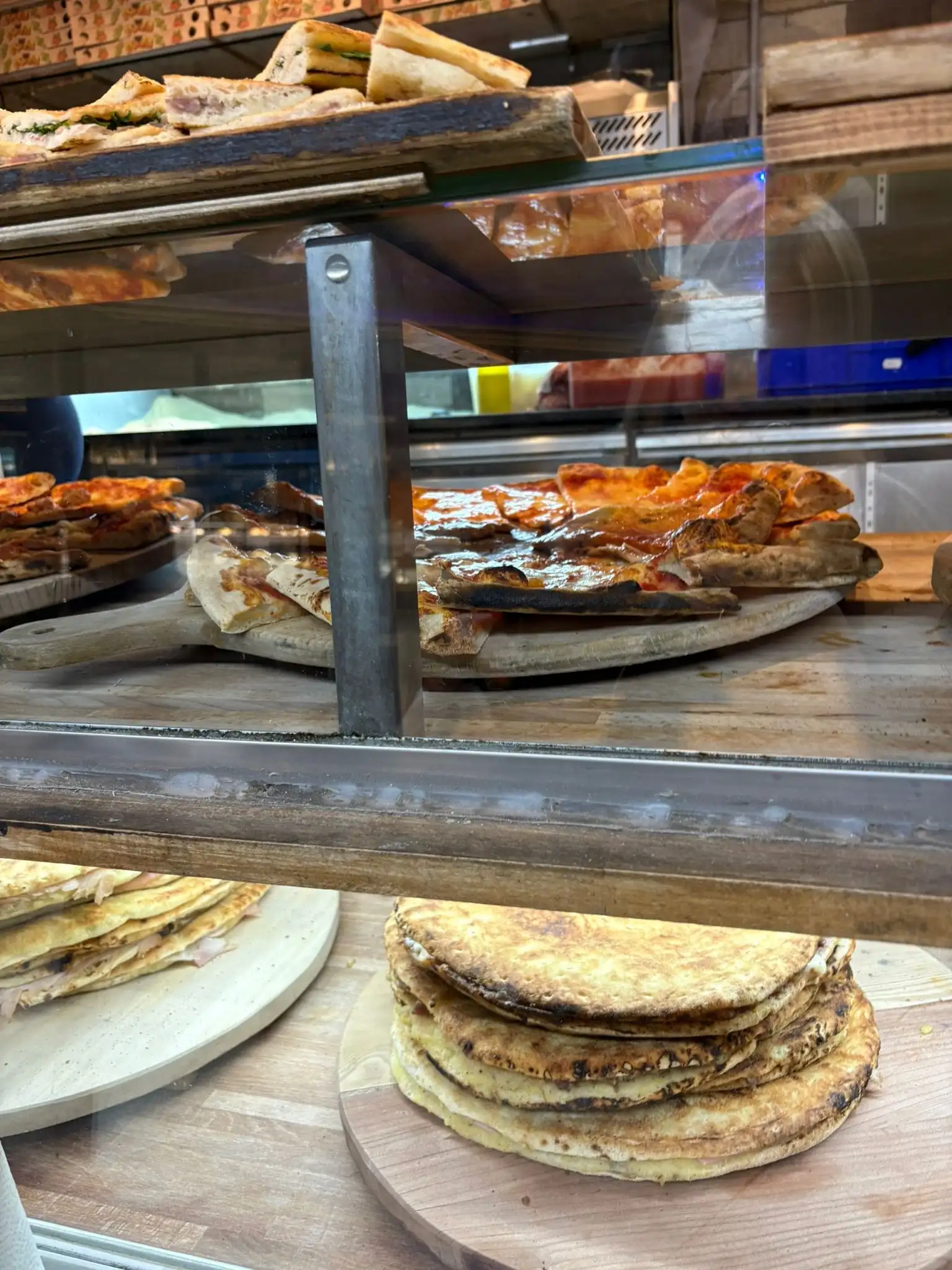 Schiacciate e pizze impilate sui taglieri di legno