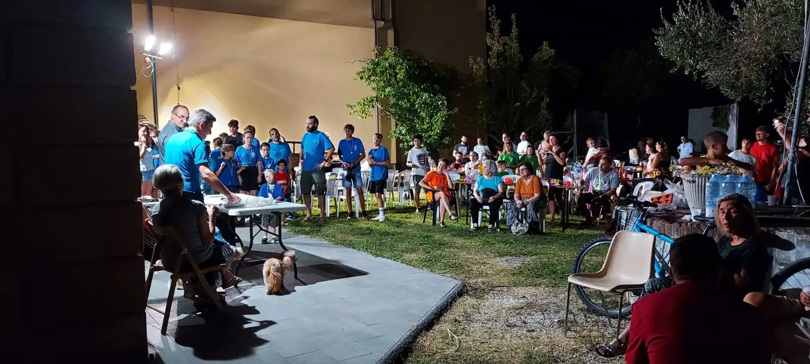 Una serata all’aperto, con i tavoli e la gente seduta sul prato
